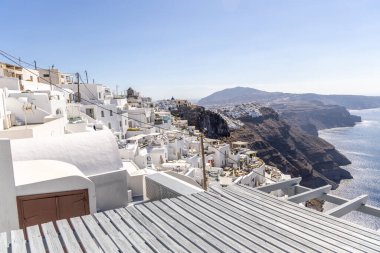Santorini, Yunanistan - 15 Ekim 2024: Santorini 'nin beyaz binalarının panoramik manzarası ve açık mavi gökyüzü olan mavi kubbeler. Klasik Yunan adası cazibesi