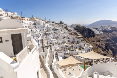 Santorini, Yunanistan - 15 Ekim 2024: Santorini 'nin beyaz binalarının panoramik manzarası ve açık mavi gökyüzü olan mavi kubbeler. Klasik Yunan adası cazibesi