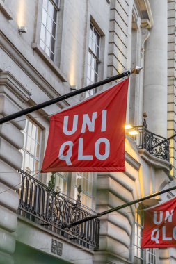 Londra, UK- 19 Eylül 2024: UNIQLO Japon dükkânı logosu Londra Regent Caddesi 'nde kırmızı bayrak dükkanı. Akşam şehir manzarası.