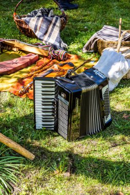 Riga, Letonya - 23 Haziran 2024: Geleneksel halk kültürü müzik festivalleri enstrümanları. Açık havada yerde akordeon var..