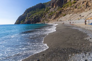 Girit, Yunanistan - 18 Ekim 2024: Girit 'te gözlerden uzak Agia Roumeli plajı, Samaria Vadisi' ndeki manzaralı dağ manzaralı çıkış, yürüyüşçüler ve plaj aşıkları için favori bir yerdir..