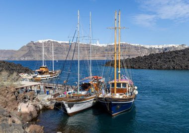 Santorini, Yunanistan - 20 Ekim 2024: Klasik Yelkenli Tekneler ve Dramatik Volkanik Uçurumlarla Tholos Naftilos Limanı.