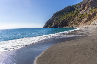 Girit, Yunanistan - 18 Ekim 2024: Turkuaz suları ve kayalık uçurumlarla uzak Agia Roumeli plajı Girit adasındaki ünlü Samaria Vadisi patikasının sonu oldu.