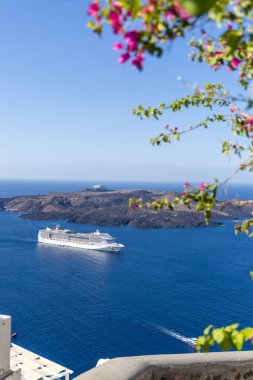 Santorini, Yunanistan - 15 Ekim 2024: Santorini 'nin Panoramik Deniz Burnu: Sakin Mavi Suları ve Engebeli Volkanı Geçen Bir Gemi Gemisi.
