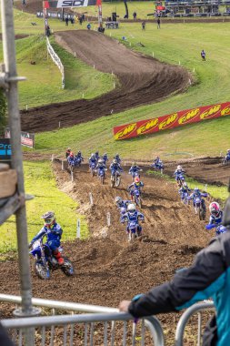 Winchester, UK- 5 Ekim 2024: Matterley Basin Grand Prix Motocross Sahnesi. Adrenalin dolu motokros pisti zafer için mücadele eden mavi elbiseli yarışçılarla dolu..