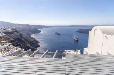 Santorini, Yunanistan - 15 Ekim 2024: Mavi Ege Denizi 'nde yelken açan yolcu gemileriyle Santorini kalderasının panoramik manzarası. Çarpıcı volkanik kayalık ve okyanus manzarası