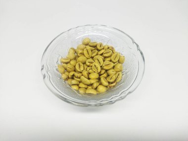 Beyaz arka planlı cam kasede yeşil kahve. Yeşil kahve, kavrulmuş olmayan normal kahve çekirdekleridir.