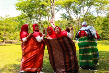 Endonezyalı bir grup kadın, zaferi Endonezya 'nın 1 Eylül 2023 tarihli bağımsızlık gününde ellerinde bayraklarla kutluyor.