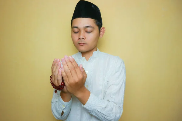 an Indonesian Muslim man of Asian descent wearing Muslim clothes and a black peci, celebrating Eid al-Adha, Eid al-Fitr. Isolated on a yellow background and with very diverse expressions