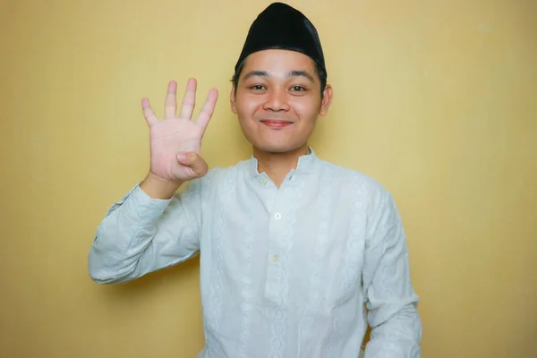 an Indonesian Muslim man of Asian descent wearing Muslim clothes and a black peci, celebrating Eid al-Adha, Eid al-Fitr. Isolated on a yellow background and with very diverse expressions