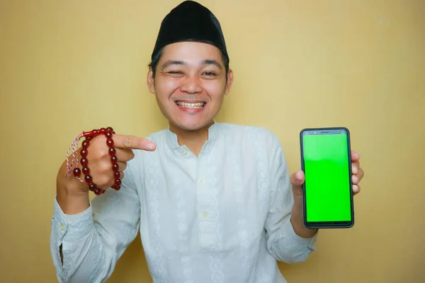 一名身穿穆斯林服装 头戴黑色胸针的亚裔印度尼西亚穆斯林男子 庆祝开斋节开斋节 隔离在黄色背景上 有各种各样的表达方式 — 图库照片