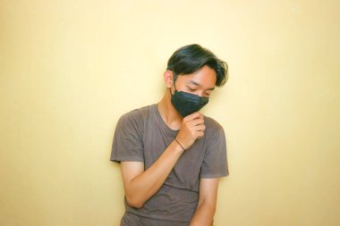 Yakışıklı bir Asyalı Endonezyalı, sarı arka planda bir sürü ifadeyle poz veriyor.