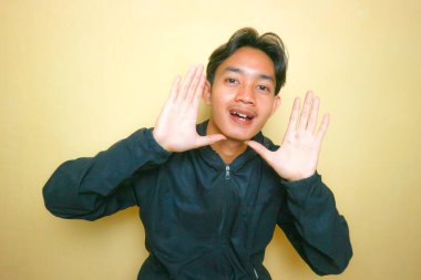 Yakışıklı bir Asyalı Endonezyalı, sarı arka planda bir sürü ifadeyle poz veriyor.