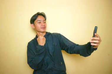 Yakışıklı bir Asyalı Endonezyalı, sarı arka planda bir sürü ifadeyle poz veriyor.