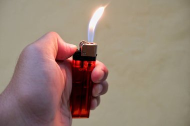 Bir insanın eli kırmızı bir gaz çakmağını tutar.