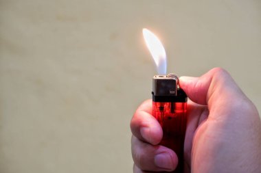 Bir insanın eli kırmızı bir gaz çakmağını tutar.