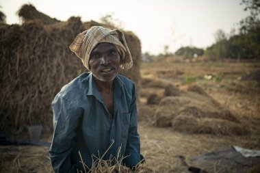 Karjat, Hindistan 27 Kasım 2022 çalışkan yerli Hintli çiftçi pirinç çiftliğinde duruyor ve arka planda kuru otlar duruyor..