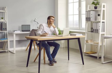 Ofiste ya da evde dizüstü bilgisayarla çalışan genç çekici iş adamının portresi, bilgisayar ekranına ve yazıya bakıyor, yeni projeler ve girişimleri düşünüyor, şirketi analiz ediyor..