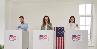 Başkanlık seçimleri sırasında oy kullanan Amerikalı seçmenler. Beyaz oy verme kabinlerinde Amerikan bayraklarıyla bekleyen üç mutlu insan grubu. ABD konseptinde seçimler