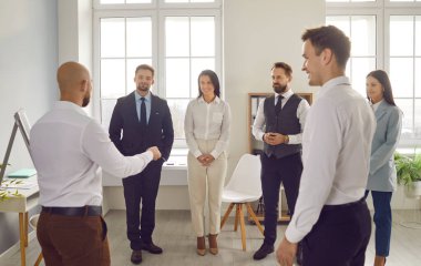 Modern ofis toplantısı sırasında pozitif iş adamları. Ekip, iş yerlerindeki meslektaşları arasında takım çalışması ve işbirliği sergileyen bir sunum ve sohbete girişiyor..