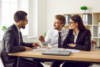 Üç iş arkadaşı ve çalışanlardan oluşan bir grup bir şeyi tartışıyor, anlaşmaya varıyor ve kontrat imzalıyor. Şirket çalışanları ofiste toplantı yapıyor ve gülümsüyor..