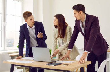 Bir grup iş arkadaşı modern ofiste birlikte çalışmak için dizüstü bilgisayar kullanmayı tartışıyorlar. Genç erkek ve bayan iş arkadaşları birlikte çalışarak yeni projeyi tartışıyor. İş ortaklığı kavramı.