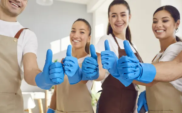 Close up of the hands of a cleaning staff team, wearing gloves and giving a thumbs up. The group of smiling cleaners demonstrates teamwork and professionalism in a home or office cleaning.