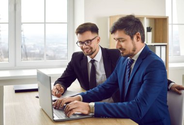 Genç başarılı beyaz adam dizüstü bilgisayarla çalışıyor şirket müşterileri için sunum yapıyor ya da iş kıyafetleri giymiş e-postalarla cevap veriyor parlak ofis masasında oturuyor.