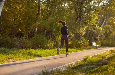 Spor beyaz kadın, spor giyimde, doğa üzerinde koşuyor. Açık hava serinletici koşusu günbatımında antrenman ve egzersizi birleştirir. Atletik Kafkasyalı kadın iş başında.
