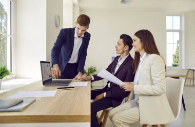 Ofisteki modern defter bilgisayarını kullanan bir iş adamı. İş arkadaşlarıyla mali analist toplantısı, dizüstü bilgisayara işaret etmek, bazı verileri paylaşmak, ve analitik grafikler, grafikler ve tablolar göstermek