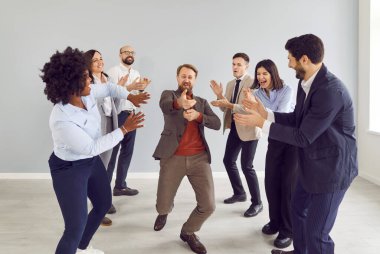 Mutlu iş adamları grup olarak ofiste eğleniyorlar. İyi bir anlaşma yaptıkları için mutlular. Şirket çalışanları içeride dans ederek başarıyı kutluyor. Takım çalışması ve takım oluşturma kavramı.