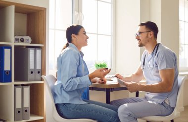 Genç bir kadın hasta muayene sırasında klinikte bir erkek doktorla ya da hemşireyle konuşuyor. Hasta şikayetlerini dinleyen bir doktor. Sağlık ve Tıp Konsepti.