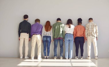 Yedi kişilik çeşitli, sessiz bir grup beyaz duvara doğru yan yana duruyor. Güneş ışığıyla dolu aydınlık odada bulunan yaratıcı çok ırklı erkek ve kadınlar çeşitlilikte birliği temsil ediyor. Pankart.