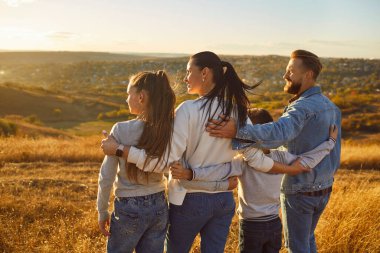 Birleşmiş bir ailenin hafta sonları ya da tatillerde dışarıda dolaşmaktan keyif almasının arkası. Birlikte manzaranın arka planında duruyorlar, doğanın güzelliği üzerinde dinleniyorlar..