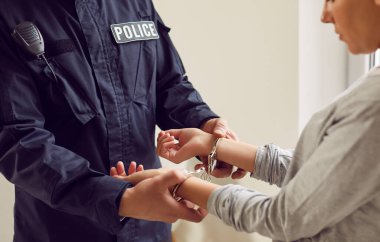 Şüpheli bir kadına kelepçe takan bir polisin yakın görüntüsü. Tutuklama, bir cezai suçla ilgili polis prosedürleri kapsamında, kadının yasalar uyarınca gözaltına alınmasıyla gerçekleşti..