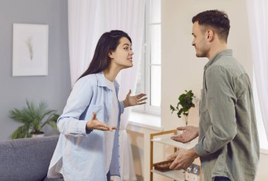 Evdeki oturma odasında kavga eden, birbirine bağıran genç bir çift. Mutsuz adam ve kadın ilişkilerde sorun yaşıyor. Evlilik kavgası ve boşanma kavramı.