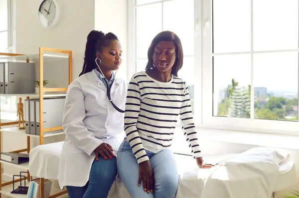 Eine Afroamerikanische Ärztin Weißen Kittel Untersucht Eine Junge Patientin Legt — Stockfoto