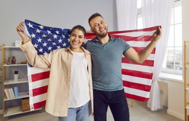 Amerikan bayrağını tutan mutlu aile çifti, Bağımsızlık Günü 'nü kutluyor. Neşeli ifade ve vatansever ruh, Amerikan vatandaşı olmanın gururunu yansıtıyor..