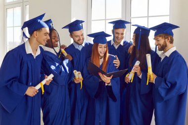 Havan ve elbise giyen, diploma sahibi çok uluslu lisansüstü öğrencileri. Saygıdeğer akademiden çeşitli akademik bir ekip içinde birlik ve başarı gösteriyorlar..