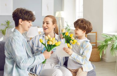 Mutlu bir anne, mutlu bir genç ve küçük oğlundan bahar çiçekleri alıyor. Uluslararası kadınlar gününü, doğum gününü, anneler gününü kutluyor. 8 Mart sarı buketi alıyor.