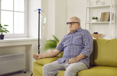 Kanepede oturan son sınıf öğrencisi. Elinde serum var. Yaşlı erkek hasta damar içi tedavi görüyor ya da vitamin tedavisi görüyor. Tedavi, sağlık, bağışıklık sisteminin bakımı