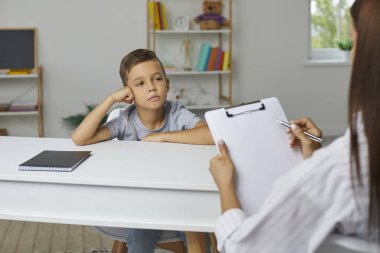 Okul danışmanı, psikolog ya da öğretmen elinde not panosu olan küçük çocukla konuşuyor, kişilik geliştirme sınavıyla ilgili sorular soruyor ve not alıyor. Psikoloji, eğitim kavramı