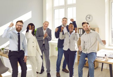 Bir grup iş adamı, kadın ve erkek kameraya bakıp evet işareti yapıyor ve ofiste gülümsüyor. Şirket çalışanları ya da bir grup personel iyi bir anlaşma yapmaktan mutluluk duyar..