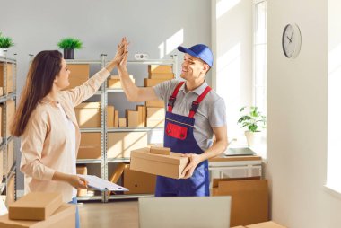 Teslimatta başarılı bir başarı. Neşeli, organize bir depo müdürü ve yükleyici işi beşlik çakarak halletti. İnsanlar parlak aydınlatılmış depo odasındaki karton kutularla çevrili..