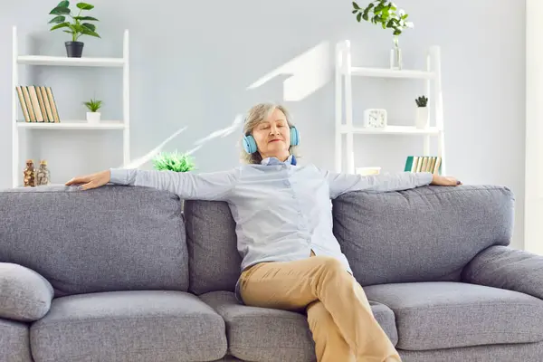 Ältere Lächelnde Entspannte Frau Sitzt Hause Auf Dem Sofa Und lizenzfreie Stockfotos