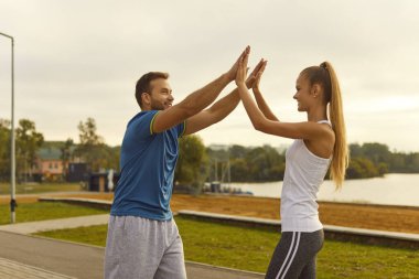 Mutlu gülümseyen sporcu çift ve kadın beşlik çakıyor spor eğitiminin başarısını kutluyor ya da doğada idmandan sonra dışarıda egzersiz yapıyor. Sağlıklı yaşam tarzı kavramı.