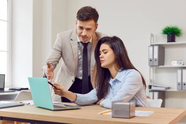 İş adamları, bilgisayardaki çeşitli ortaklar, modern ofis ortamında çalışan erkek ve kadın iş arkadaşları. İş adamı genç iş kadınına yardım ediyor, birlikte çalışıyor, projeyi tartışıyor, destek oluyor. 