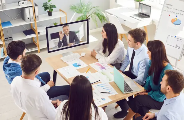 İş adamlarından oluşan bir grup, online video konferans odasında modern ofisteki çalışma masasında bilgisayardan online video görüşmesi yapıyorlar. İş teknolojileri kavramı.