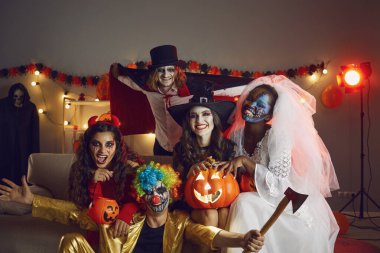 Korkunç korku kostümleri içinde çeşitli gülümseyen gençlerin portresi Cadılar Bayramı 'nı dekore edilmiş evde kutluyor. Maskeli balodaki mutlu çoklu etnik arkadaşlar Aziz Arifesi parti kutlamalarının tadını çıkarın..