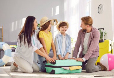 Aileler ve çocukların yaz gezisinden önce valizlerini topladıkları mutlu an. Baba, anne, oğul ve kız evde oturuyorlar. Yaz tatiline gitmeye hazırlar..